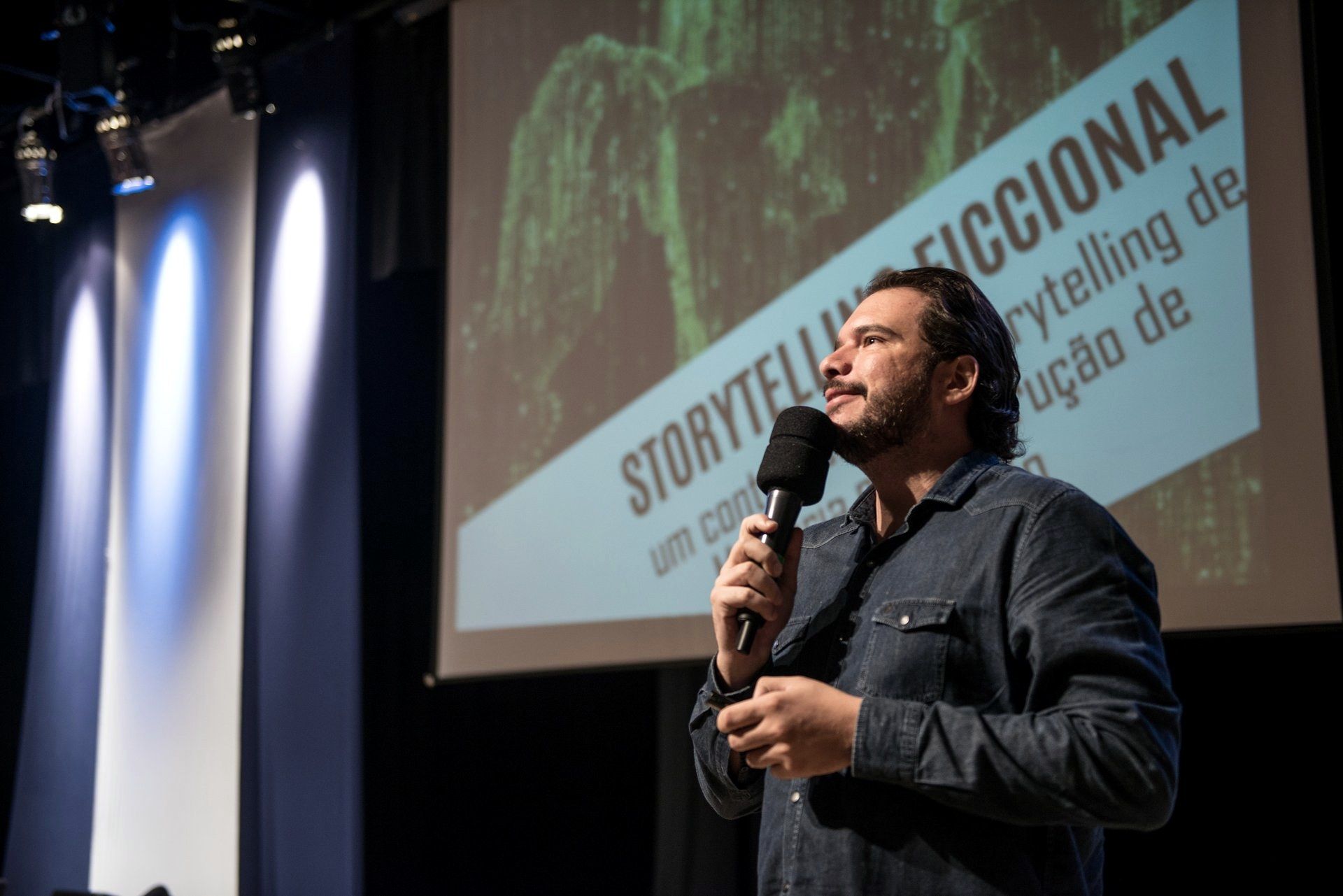 Fernando Palacios falando no palco, com um slide intitulado storytelling ficcional ao fundo