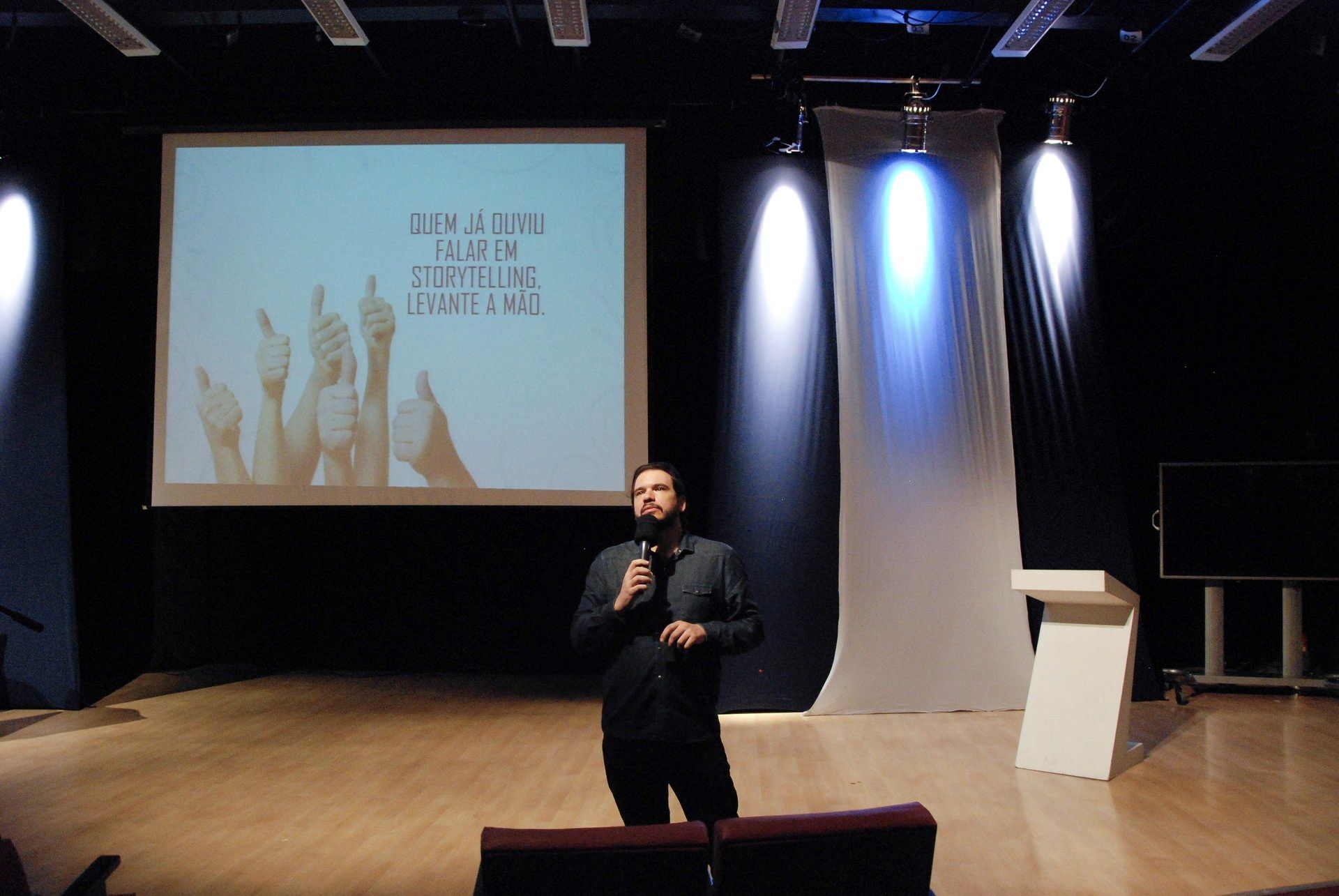 Fernando Palacios no palco, abrindo uma palestra de storytelling, com a tela ao fundo perguntando quem já ouviu falar de storytelling