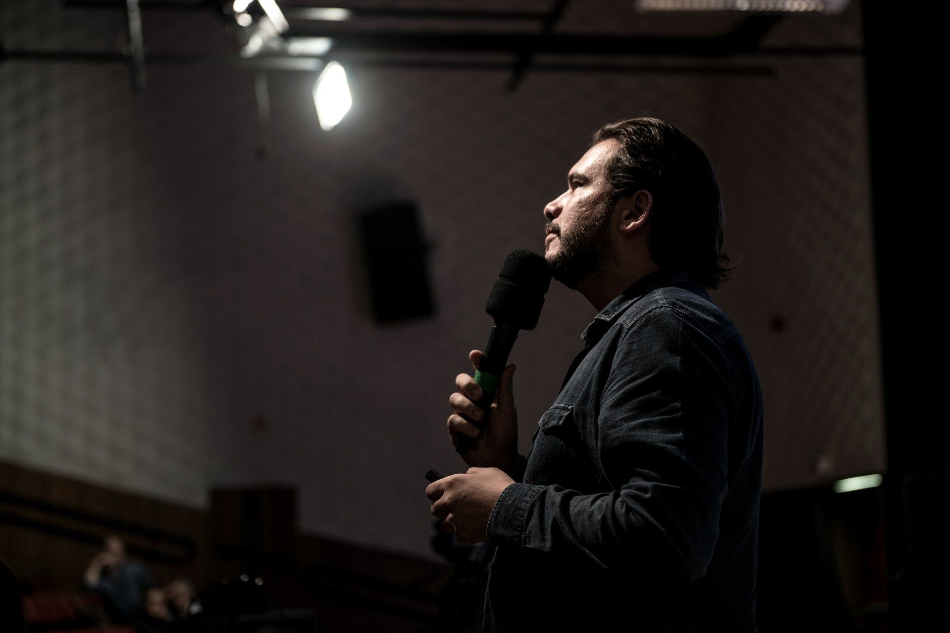 Fernando Palacios num palco escuro com microfone